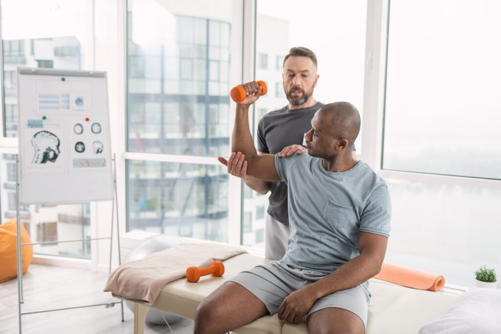I am strong. Nice young man looking at his muscles while exercising his coach